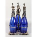 A PLATED THREE BOTTLE DECANTER SET, with "BRISTOL BLUE" DECANTERS, having grape and vine mounts.