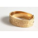 AN ENGRAVED GILT METAL BANGLE.