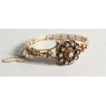 A LADIES' 14CT GOLD AND DIAMOND BANGLE WATCH with a flowerhead design hinged cover set with a