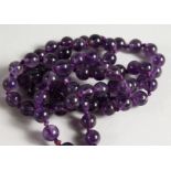 AN AMETHYST BEAD NECKLACE. 27ins long.