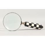 A MAGNIFYING GLASS with chequered handle.