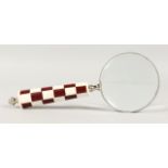 A MAGNIFYING GLASS with chequered handle.