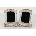 A PAIR OF SILVER AND COLOURED ENAMEL PHOTOGRAPH FRAMES with butterflies and flowers. 8.5ins x 6ins.