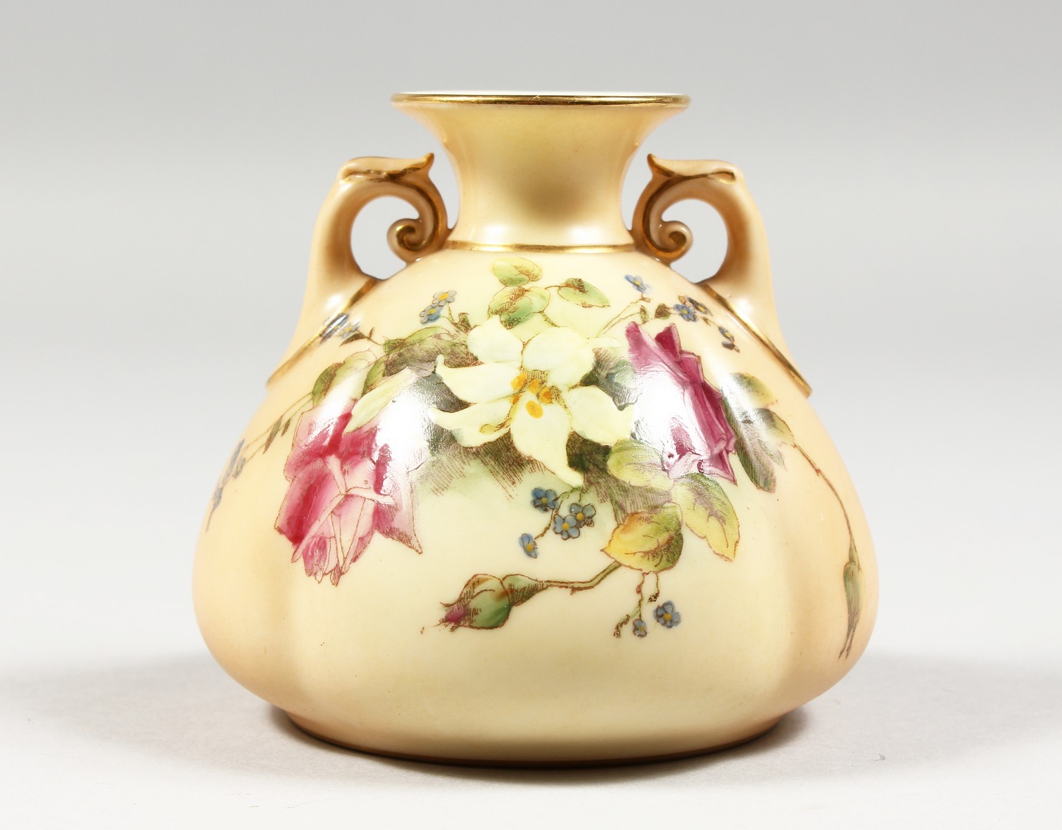 A ROYAL WORCESTER BLUSH IVORY TWO HANDLED VASE painted with roses and lilies, date code 1914,
