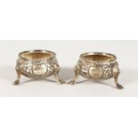 A SMALL PAIR OF VICTORIAN CIRCULAR SALTS, repousse body on three pad feet. London 1816.