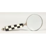 A MAGNIFYING GLASS with chequered handle.