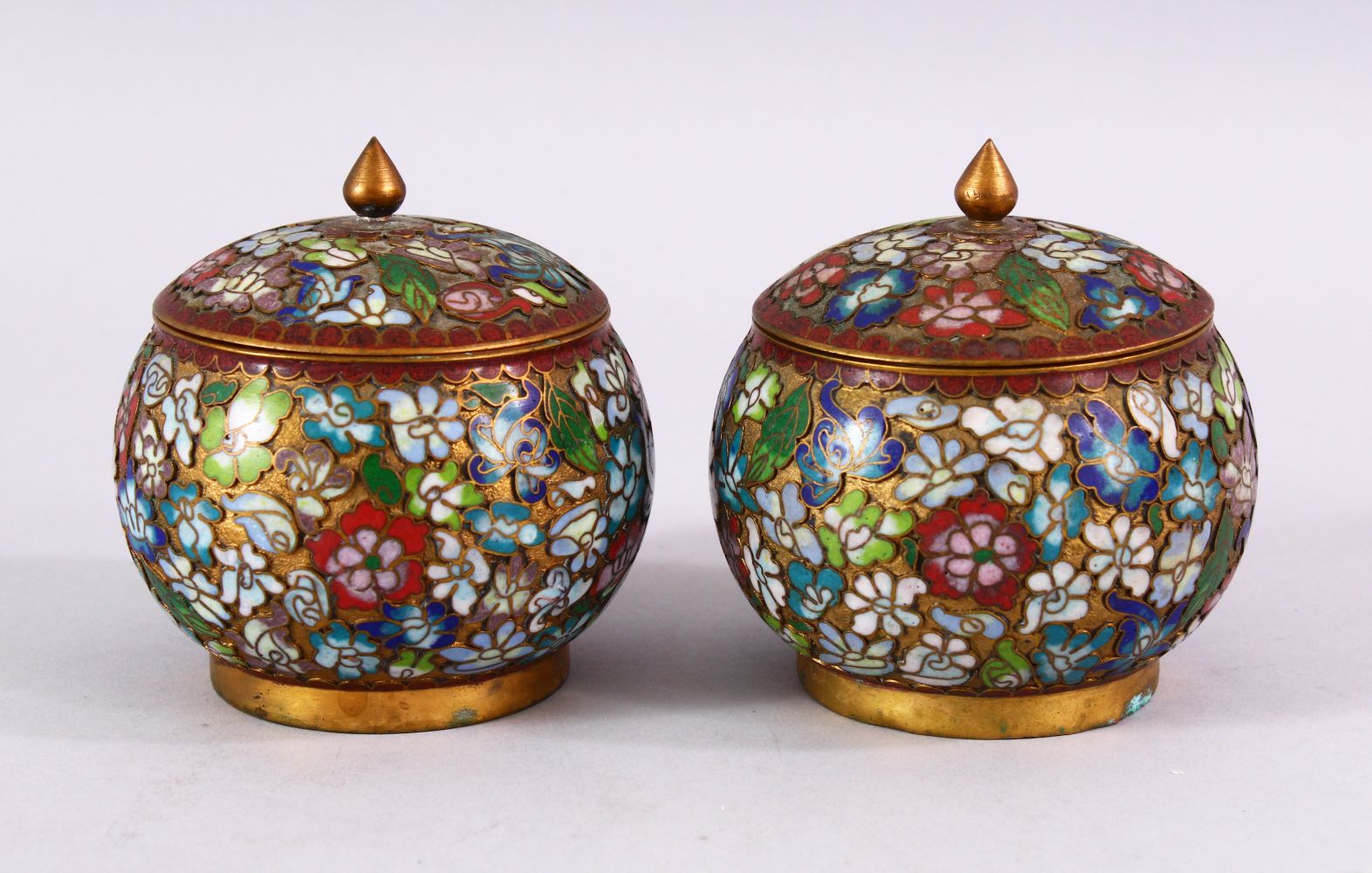 A PAIR OF CHINESE CLOISONNE LIDDED JARS, each decorated with raised floral decoration, 9cm high x