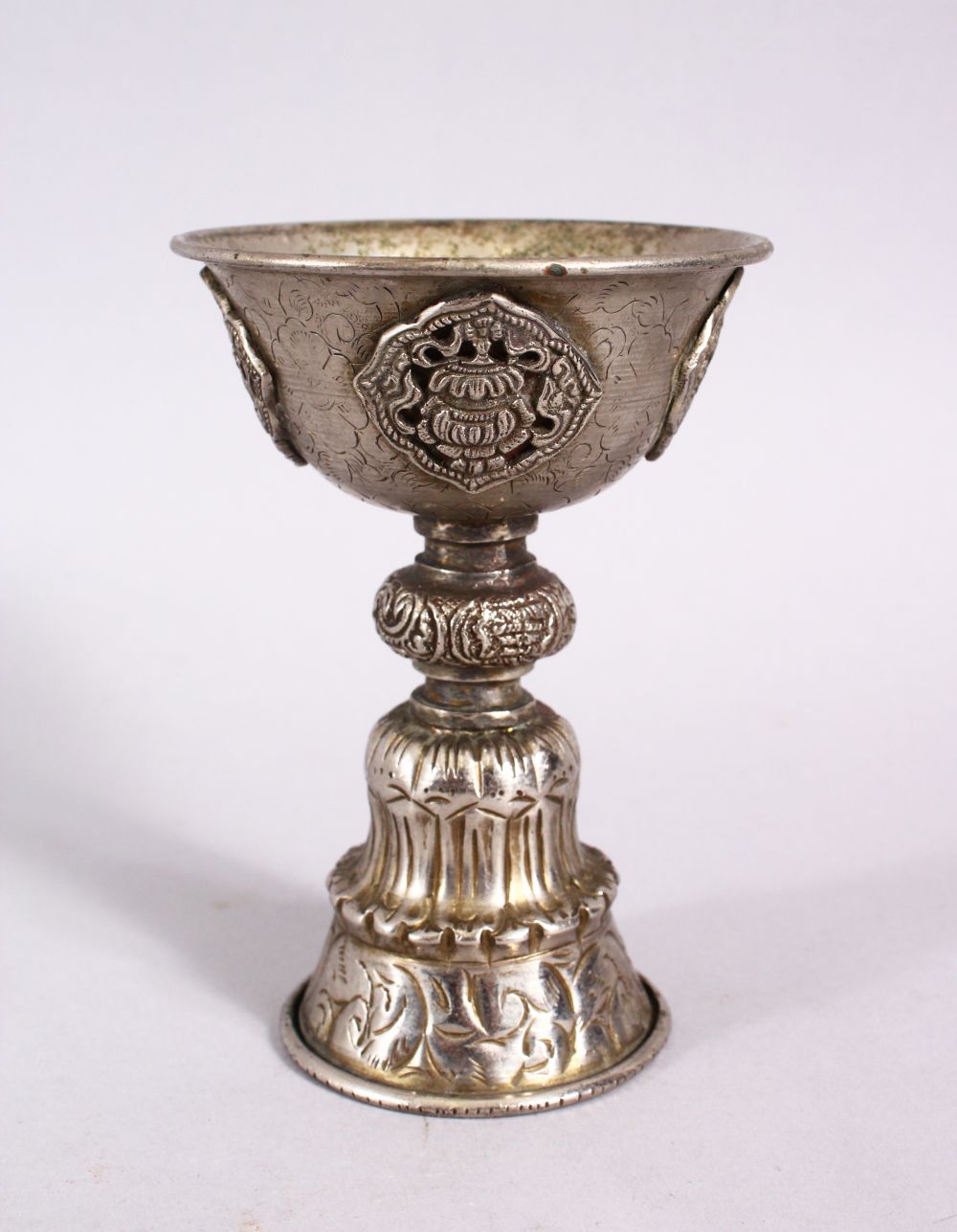 A GOOD 19TH CENTURY SINO TIBETAN WHITE METAL STEM CUP, with buddhistic object decoration, 11.5cm