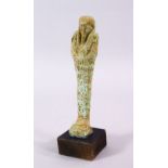 A CARVED POTTERY EGYPTIAN SHABTI, stoof upon a wooden base, 19cm high.