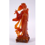 A CHINESE CARVED AGATE FIGURE OF GUANYIN, holding a fan and robes, on a carved wooden base, 19cm