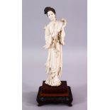 A 19TH CENTURY CHINESE CARVED IVORY FIGURE OF GUANYIN, stood holding a fan, on a carved wooden base,