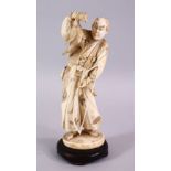 A FINE JAPANESE MEIJI PERIOD CARVED IVORY OKIMONO OF A HUNTSMAN, stood holding his catch with his