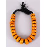 A LARGE ISLAMIC AMBER / BAKELITE CARVED ROUNDEL BEAD NECKLACE with 22 beads each approx, 4cm
