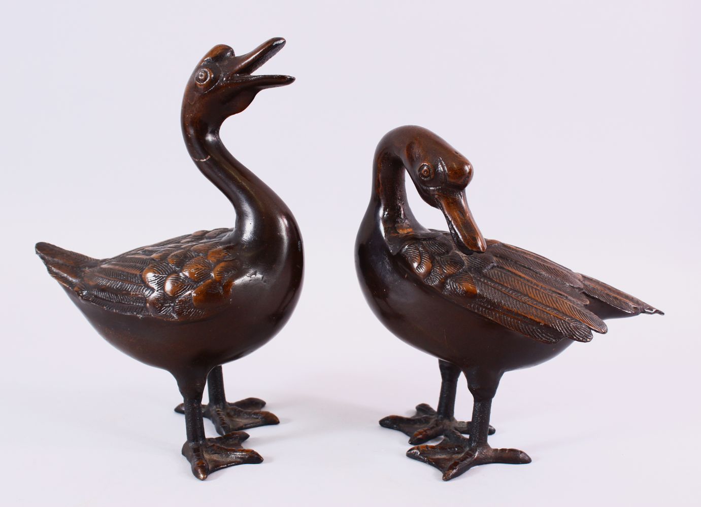 A PAIR OF CHINESE BRONZE FIGURES OF DUCKS, both in standing positions with detailed carvings of