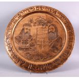 A LARGE EMBOSSED COPPERED JEWISH DISH, with two figures, with script on a board, with borders of