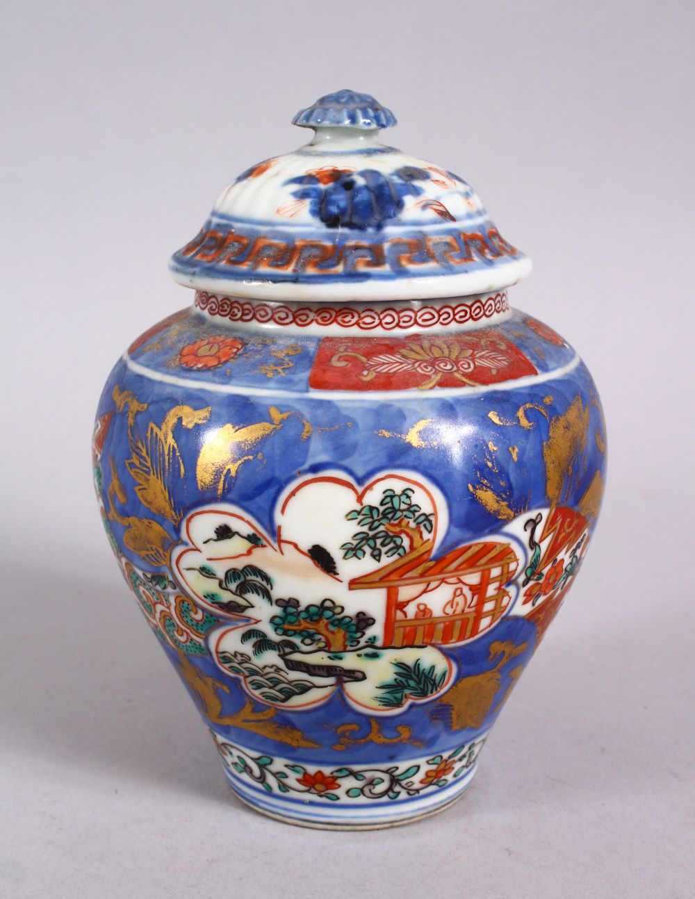 AN 18TH CENTURY JAPANESE BLUE, WHITE AND IRON RED PORCELAIN ARITA JAR & COVER, with landscape