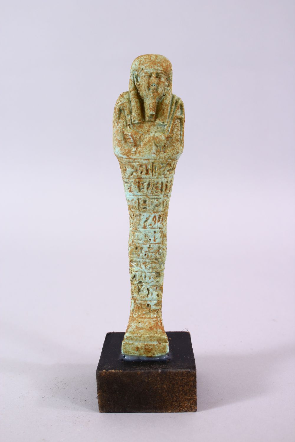 A CARVED POTTERY EGYPTIAN SHABTI, stoof upon a wooden base, 19cm high. - Image 2 of 4