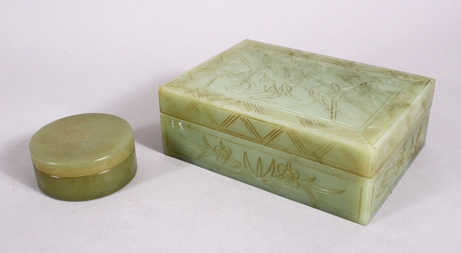 TWO CHINESE CARVED JADE BOXES, one of cylindrical form and carved with flora, 6cm, the other of