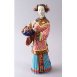 A CHINESE FAMILLE ROSE POTTERY FIGURE OF A LADY HOLDING FLORA, the underside with calligraphy and