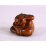 A JAPANESE MEIJI PERIOD CARVED BOXWOOD NETSUKE OF A MAN IN HIS LAP- the figure with his head down in