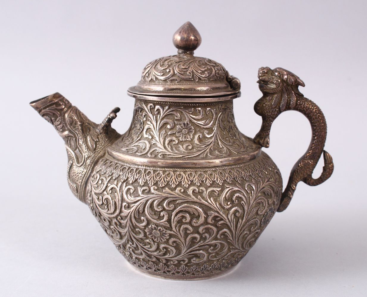 A GOOD 19TH CENTURY TURKISH SOLID SILVER TEAPOT carved with formal foliage and a dog style handle,