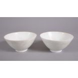 A PAIR OF CHINESE MING STYLE MONOCHROME CARVED PORCELAIN TEA BOWLS, with carved decorations of