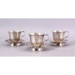 A SET OF THREE 19TH CENTURY CHINESE SILVER CUP & SAUCERS, each carved with a display of flora and