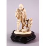 A JAPANESE MEIJI PERIOD CARVED IVORY OKIMONO GROUP - MONKEY TRAINER - the man stood with a monkey to