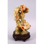 A CHINESE CARVED JADE FIGURE OF TWO LION DOGS, the dogs playing upon wooded outcrops, upon a