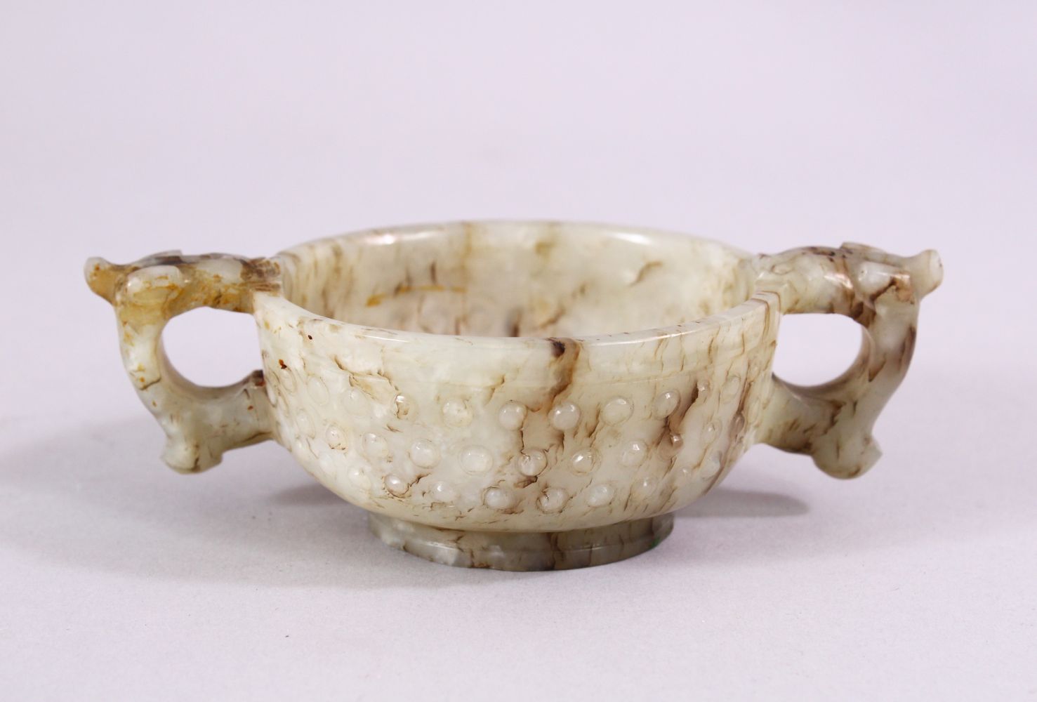 A CHINESE CARVED JADE ARCHAIC STYLE TWIN HANDLE CUP, with chilong handles, and boss decoration, 11cm