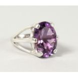 A SILVER OVAL CUT AMETHYST STONE RING.