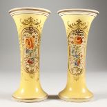 A PAIR OF YELLOW TRUMPET SHAPED VASES painted with flowers. 7ins high.