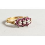 AN 18CT GOLD RUBY AND DIAMOND TRIPLE FLOWER HEAD RING.