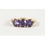 A 10K YELLOW GOLD THREE-STONE AMETHYST RING.