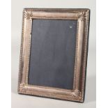 AN UPRIGHT PHOTOGRAPH FRAME with bead and shell border. 8.5ins x 6.5ins.