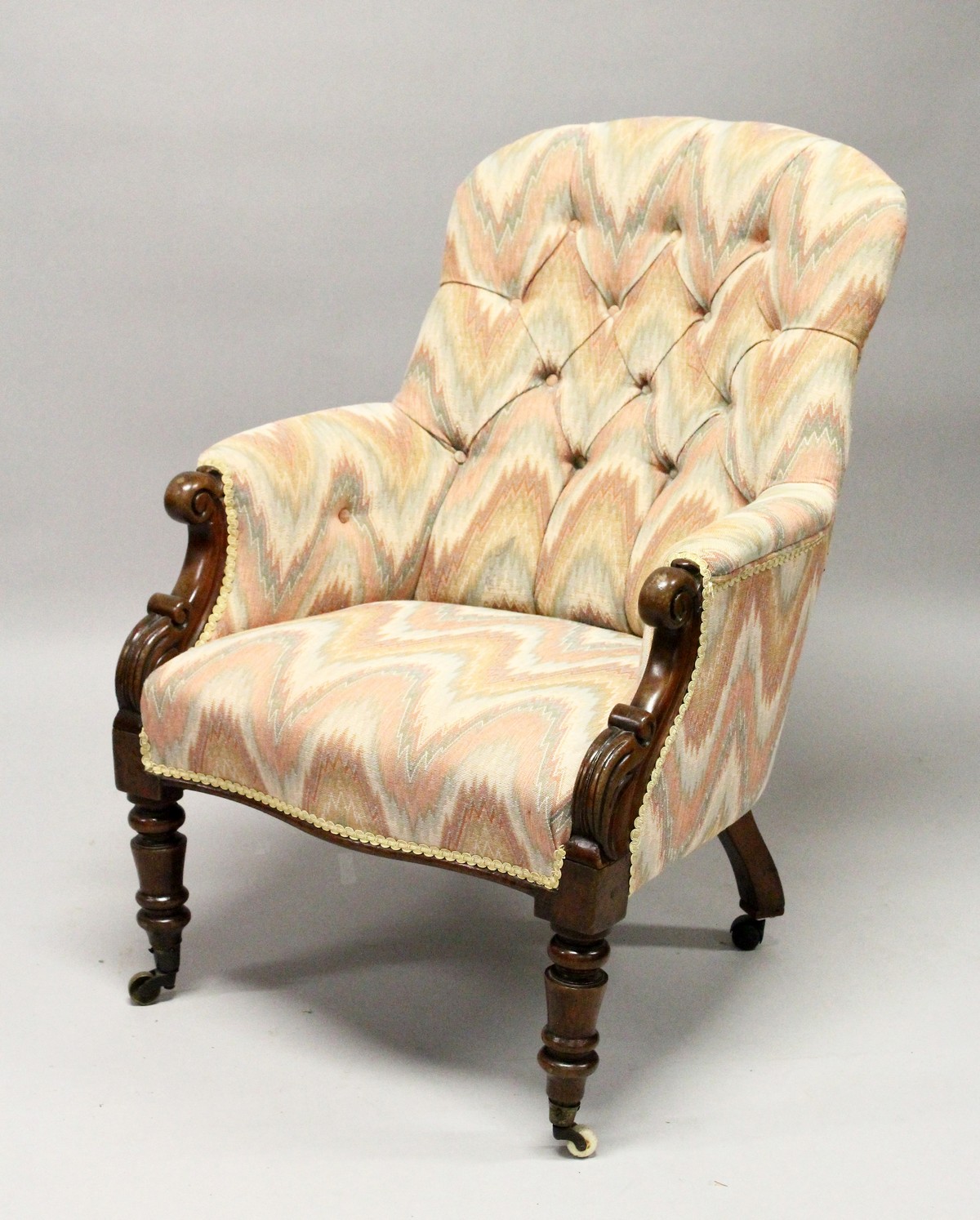 A 19TH CENTURY MAHOGANY FRAMED BUTTON UPHOLSTERED ARMCHAIR, with carved "C Scroll" arm caps,