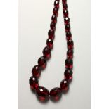 A LONG STRING OF CHERRY AMBER BEADS.