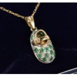 A 9CT GOLD, EMERALD AND DIAMOND BABIES BOOT PENDANT on a chain.