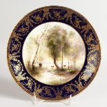 A ROYAL WORCESTER PLATE painted with cattle beside a lake beneath a blue and gilt border by George