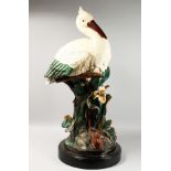 A LARGE MAJOLICA STORK STICK STAND, standing beside an open flower, on a circular base. 40ins high.