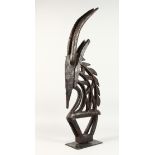 A BAMBARA TRIBE CARVED WOOD FIGURAL HEADDRESS, on a later stand. 33.5ins high.