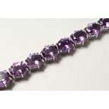 A SILVER OVAL CUT FIFTEEN STONE AMETHYST LINE BRACELET.