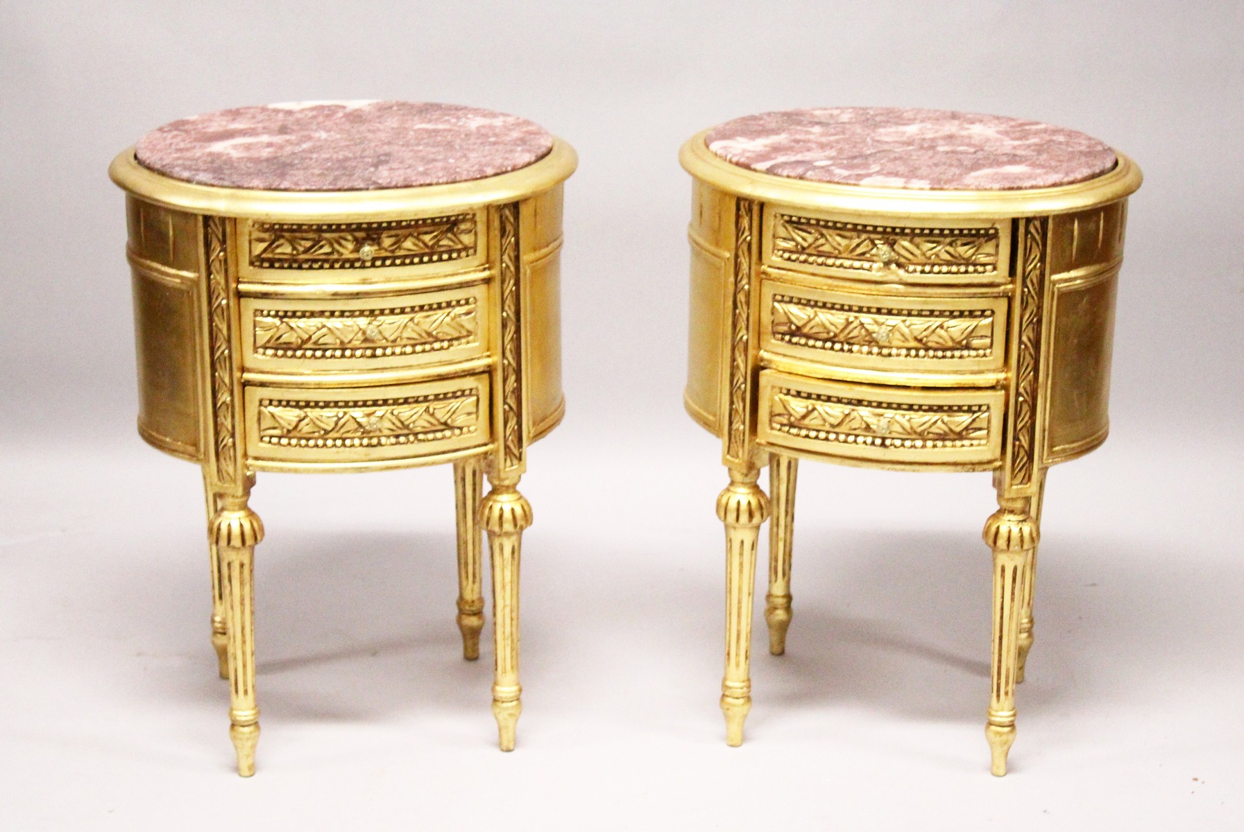 A GOOD PAIR OF GILTWOOD OVAL BEDSIDE CABINETS with marble tops.