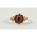 A 9CT YELLOW GOLD AND REDSTONE FLOWER RING.