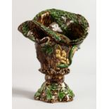 A SMALL MAJOLICA BROWN GLAZED VASE with fruiting vines. 7ins high.