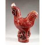 A RED GLAZED POTTERY MODEL OF A CHICKEN. 14ins high.