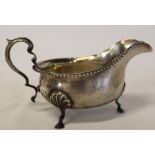 Silver sauce boat with gadrooned rim on three hoof feet by the Goldsmiths & Silversmiths Company