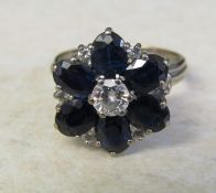 Tested as 9ct white gold diamond and sapphire flower ring, central diamond 0.25 ct, size M, total