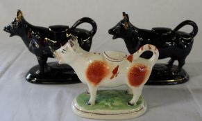 Pair of black cow creamers & single brown & white example