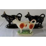 Pair of black cow creamers & single brown & white example